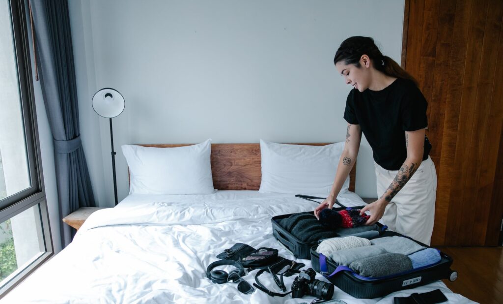 a woman in black shirt packing things in the luggage