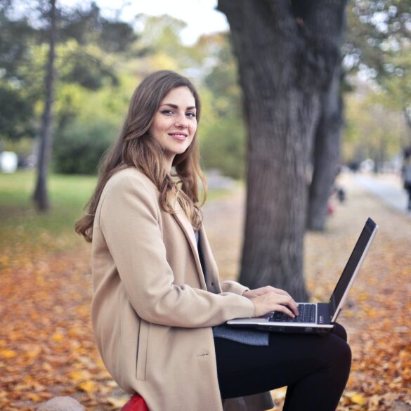 joyful confident woman using netbook in park