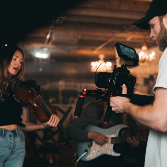 man taking a video of a woman carrying a violin
