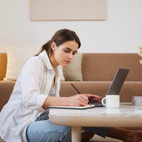 young woman using laptop and taking notes