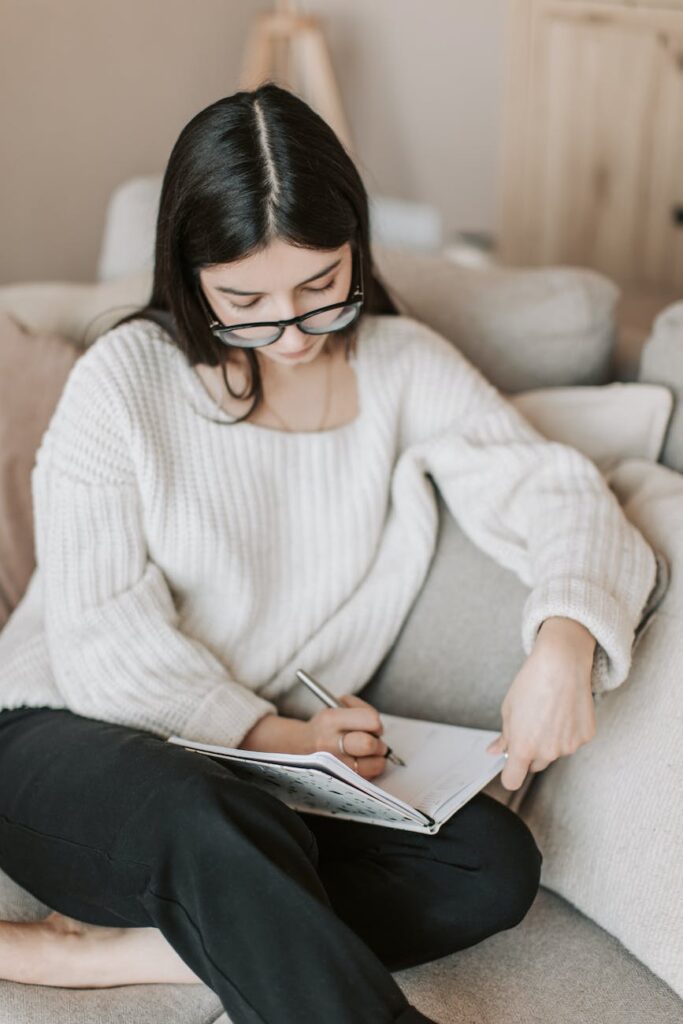 focused young woman writing agenda in diary
