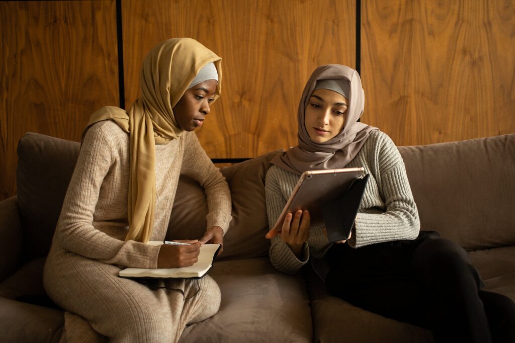 multiethnic muslim women using tablet and taking note