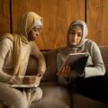 multiethnic muslim women using tablet and taking note