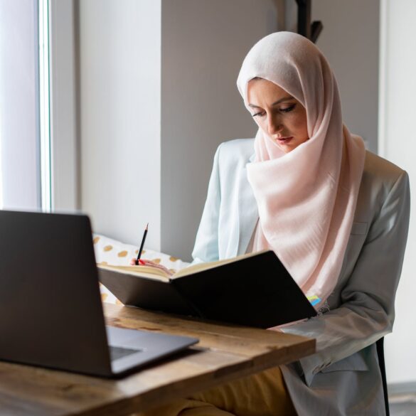 woman in white hijab sitting on chair in front of laptop computer