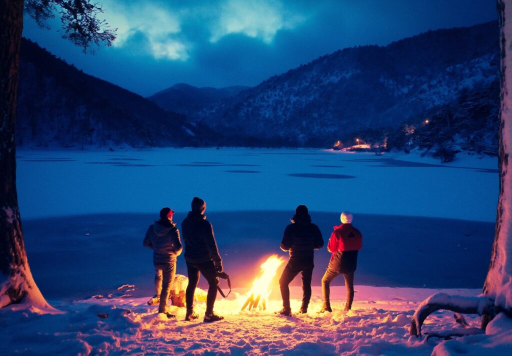group of tourists near bonfire in winter highlands