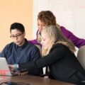 closeup photo of three person looking at macbook air