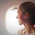 selective focus photo of woman sitting on chair looking outside window on plane