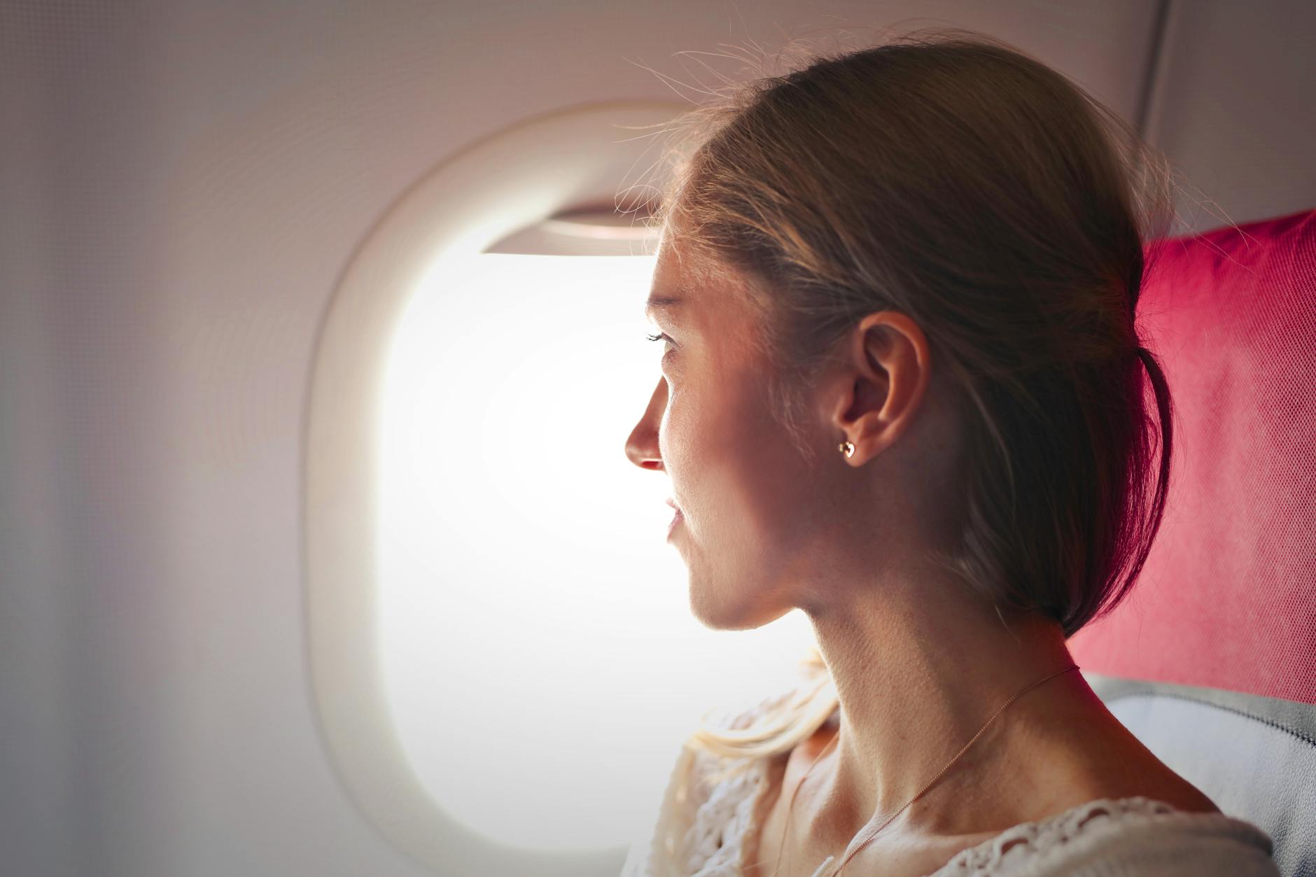 selective focus photo of woman sitting on chair looking outside window on plane