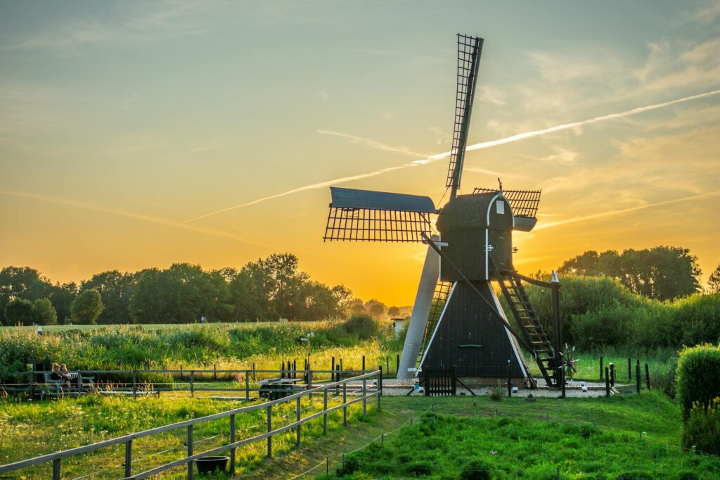 black and white wind mill in green field under yellow skies