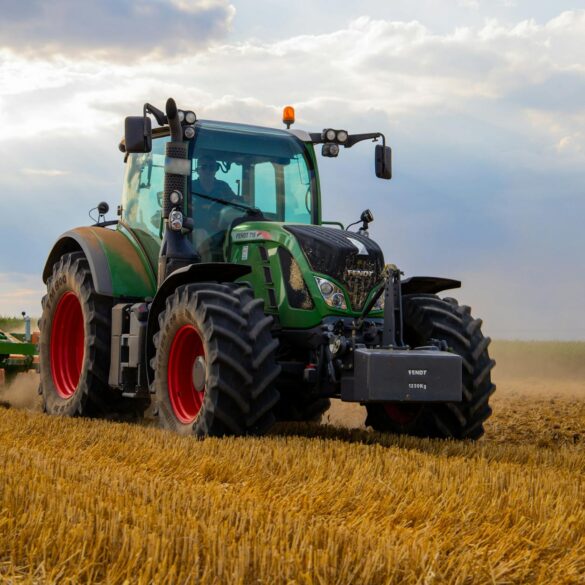 green tractor plowing the fields on focus photography