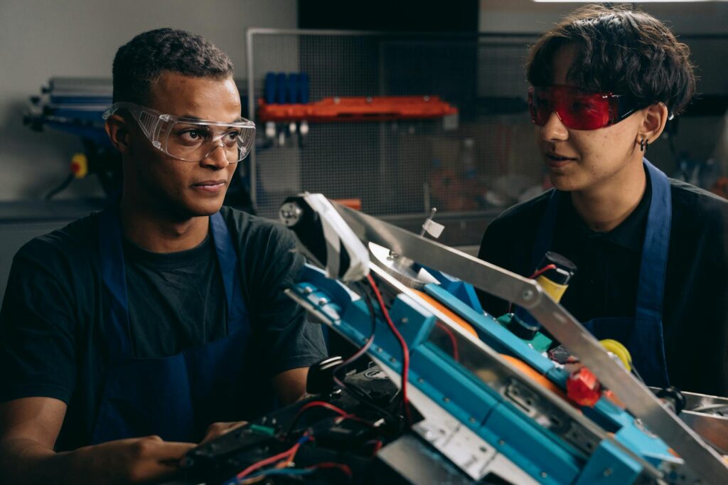 two boys wearing safety glasses near a metal frame